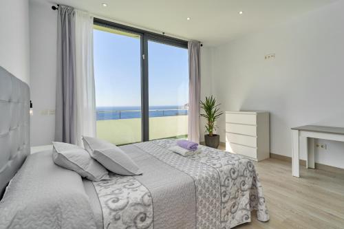 a bedroom with a bed and a large window at Villa Joya del Mediterraneo in Almuñécar