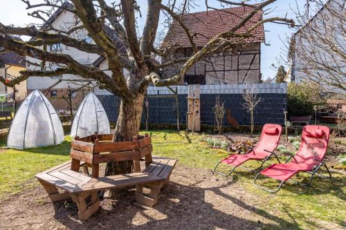 a tree and a bench and a red chair at Winzercafé Neipperg in Brackenheim