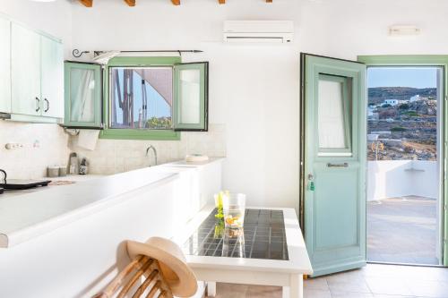a kitchen with green and white cabinets and a table at Paros - Sikinos Sunset in Sikinos