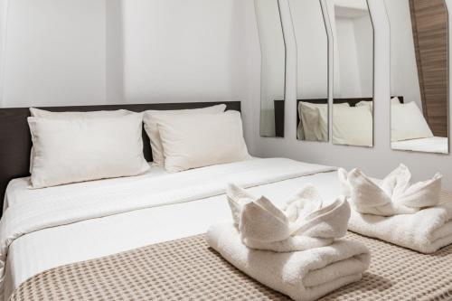 a bedroom with two beds with white pillows and mirrors at Sunset Horizon Villa in Mikonos