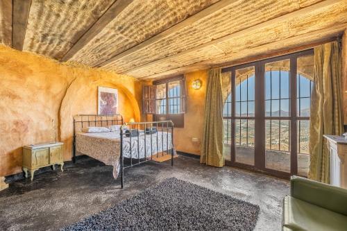 a bedroom with a bed and a large window at Casa Rural Ermita de las eras in Algarinejo
