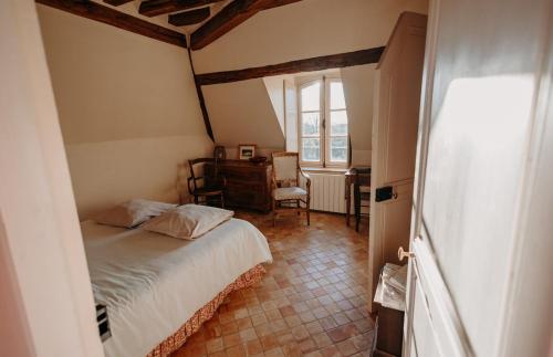 a bedroom with a bed and a desk and a window at La Maison de Melmont in Roumare