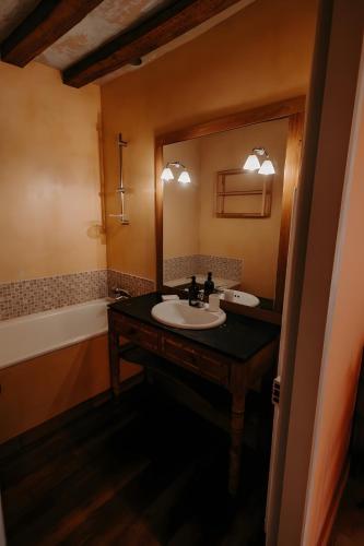 a bathroom with a sink and a mirror and a tub at La Maison de Melmont in Roumare