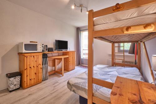 a bedroom with a bunk bed and a desk at Prapoutel pied des pistes in Les Adrets