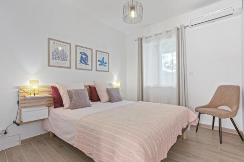 a white bedroom with a large bed and a chair at Pomme Reinette in Le Val