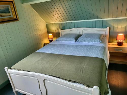 a white bed in a room with two lamps at Maison De Bord De Mer in Pirou