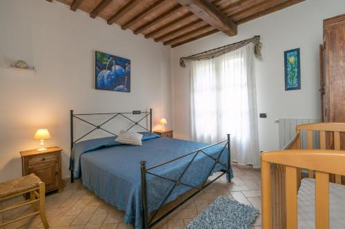 a bedroom with a blue bed and a window at Stupendo rustico in pietra in Castellina Marittima