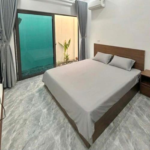a large bed in a bedroom with a large window at De Paris Homestay in Cửa Lô