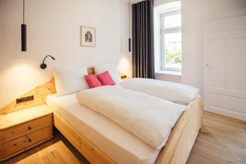 a bedroom with a bed with white sheets and red pillows at Freienfeldhof Pink Lady in Lagundo