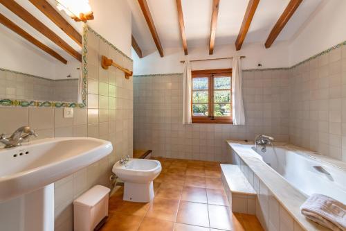 a bathroom with a tub and a toilet and a sink at Villa La Plana in Pollença