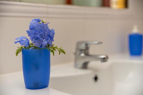 a blue vase with blue flowers sitting on a sink at Appartamento del Pellicano in Olbia