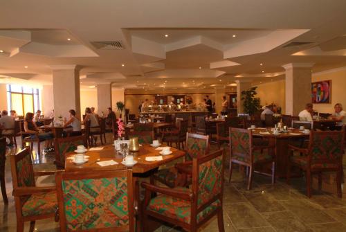 ein Restaurant mit Holztischen und Stühlen und einer Bar in der Unterkunft Bel Air Azur Resort (Adults Only) in Hurghada