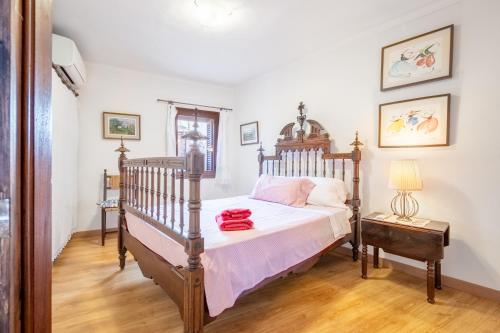 a bedroom with a wooden bed with white sheets and pink pillows at Can Vidal in Campanet