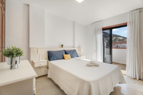 a white bedroom with a bed and a large window at Atico cardon beach in Costa Adeje