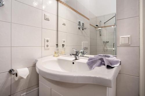 a white bathroom with a sink and a shower at Traumschlößchen 100 m vom Strand in Heringsdorf
