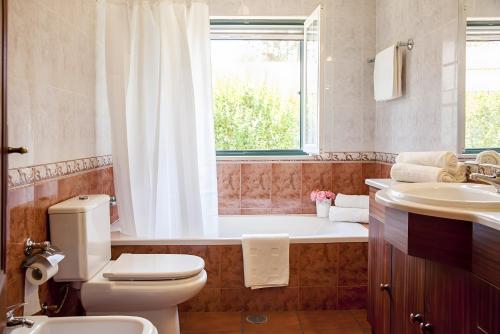 a bathroom with a tub and a toilet and a sink at Casa dos Pinheiros in Giz