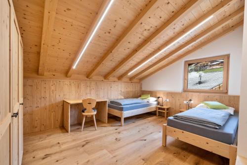 a bedroom with two beds and a desk at Parliflhof Apt Laugenblick in Meltina