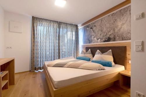 a bedroom with a bed and a large window at Noreia Pitla in Ortisei