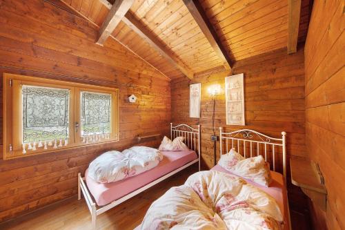 a bedroom with two beds in a wooden cabin at Orserose Chalet 4 Al Vant in Forno di Zoldo