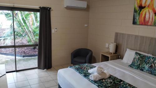 a bedroom with a bed and a chair and a window at Tully Motel in Tully