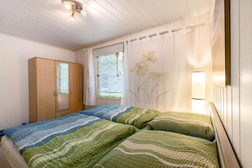 a bedroom with a bed with green and blue sheets at Ferienbungalow 1 in Boitzenburg in Boitzenburg