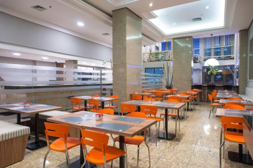 ein Restaurant mit Tischen und Stühlen in einer Cafeteria in der Unterkunft Hotel Continental Business - 200 metros do Complexo Hospitalar Santa Casa in Porto Alegre