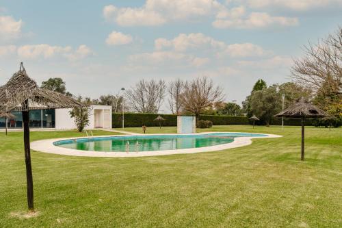 a swimming pool in a yard with umbrellas at Paradise Villa in Esposende