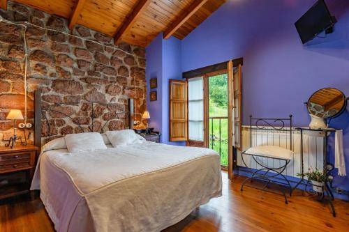 a bedroom with a bed and a stone wall at La Pumarada in Villaviciosa