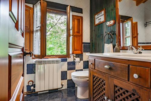 a bathroom with a toilet and a sink and a window at La Pumarada in Villaviciosa