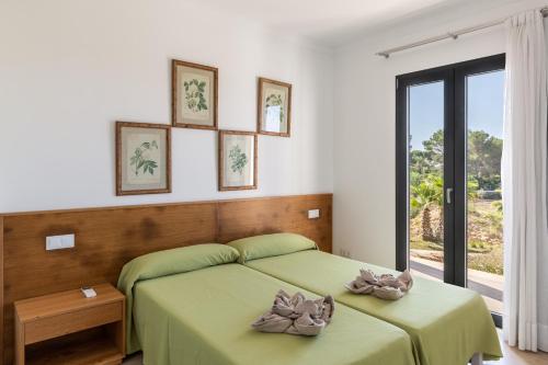 a bedroom with a green bed and a window at Colonies in Ses Salines