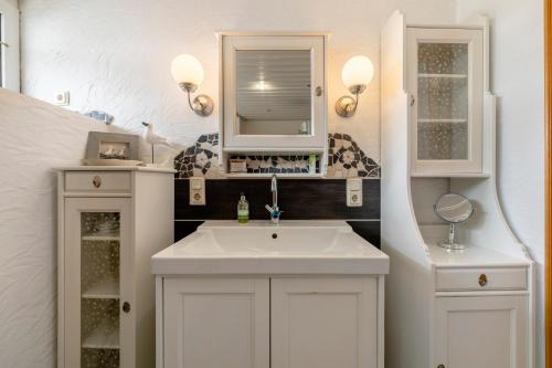 a bathroom with a white sink and a mirror at Heimatglück Vulkaneifel mit Sauna in Salm