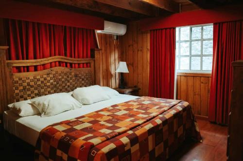 a bedroom with a large bed with red curtains at Cumbres Hotel y Cabañas in Gómez Farías