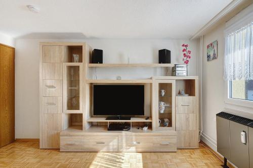 a living room with a tv in a wooden entertainment center at Ferienwohnung Honacker in Steißlingen