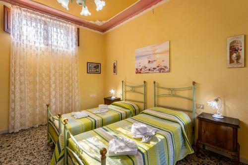 two beds in a room with yellow walls at Casa Margherita in Nebida