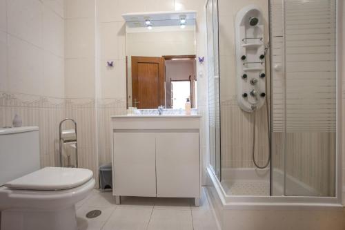 a white bathroom with a toilet and a shower at Your Secret in Lagos in Lagos