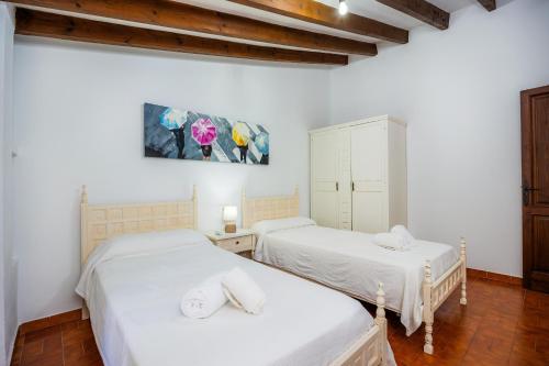 two beds in a room with white walls and wooden floors at Villa Piedra in Pollença