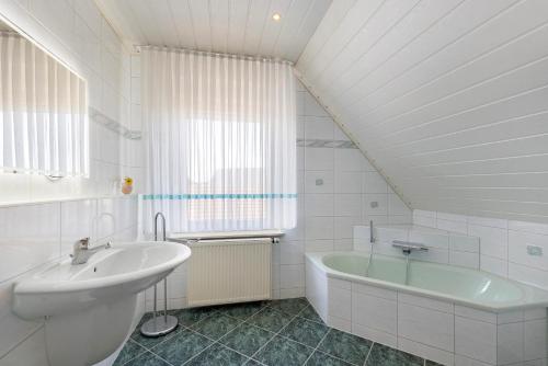 a white bathroom with a sink and a tub at Ferienwohnung mit Charme in Peitz