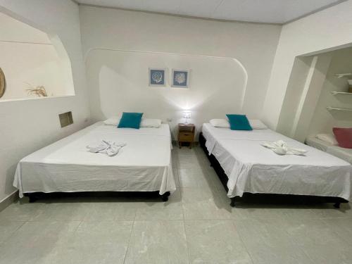 two beds in a white room with at Apartasuite tolu in Tolú