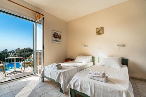 two beds in a room with a balcony at Anemona studio C in Kefallonia