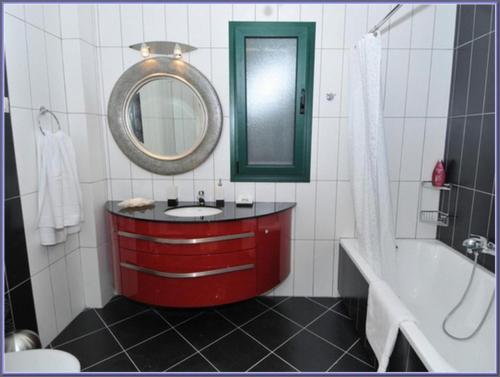 a bathroom with a red sink and a tub and a mirror at Sami Beach Villas Fedra in Sami