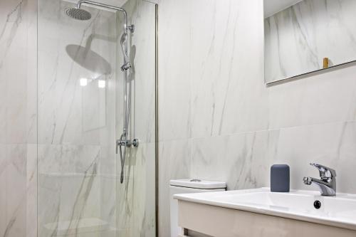 a white bathroom with a shower and a sink at Casa do Mestre T2 in Vila de Punhe