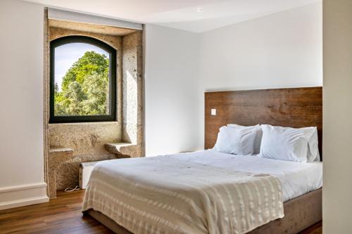 a bedroom with a large bed with a window at Casa do Mestre T2 in Vila de Punhe