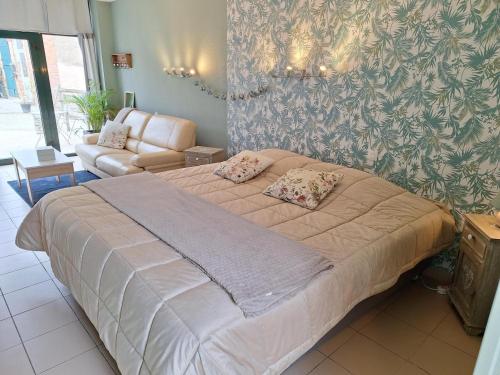 a large bed in a room with a couch at Studio du Meslay - Fyé in Fyé