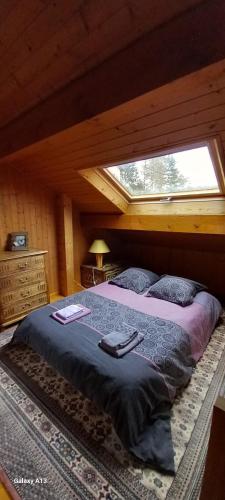 a bedroom with a large bed with a window at Chalet Jura in Doucier