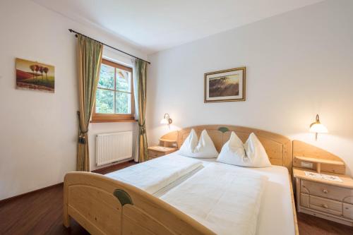 a bedroom with a large bed with white sheets at Tischlerhof - Typ B mit Balkon in Tirolo