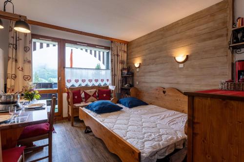 a bedroom with a bed and a table and a window at Le cheval blanc E7 in Valmorel