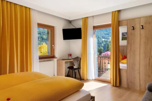 a bedroom with a yellow bed and a window at Veltierhof Villnöß in Funes
