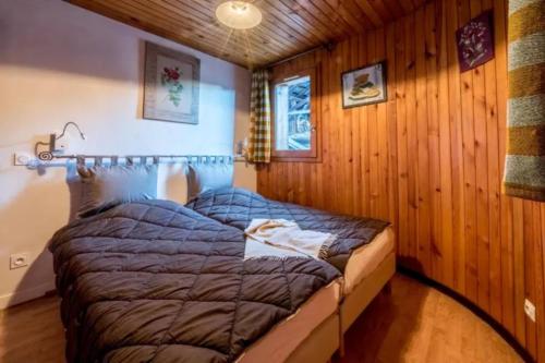 sypialnia z łóżkiem w pokoju z drewnianymi ścianami w obiekcie Le Génépi w mieście La Plagne Tarentaise