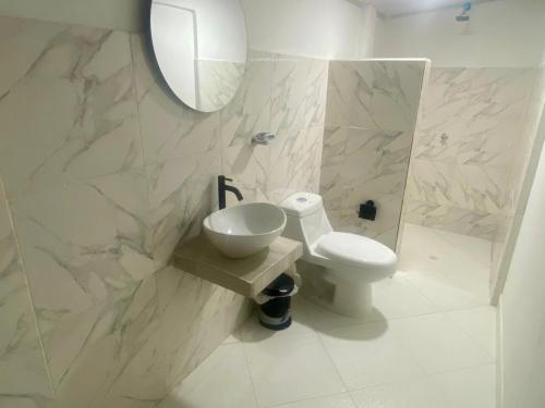 a bathroom with a toilet and a sink and a mirror at Apartasuite tolu in Tolú
