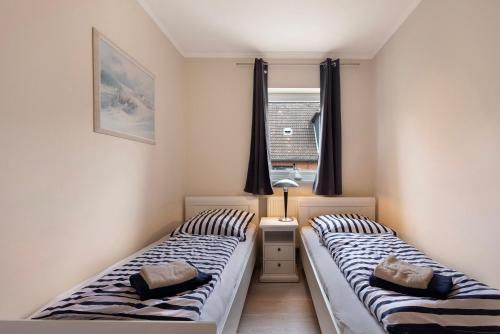two twin beds in a room with a window at Sabines Ferienwohnung 2 in Glückstadt